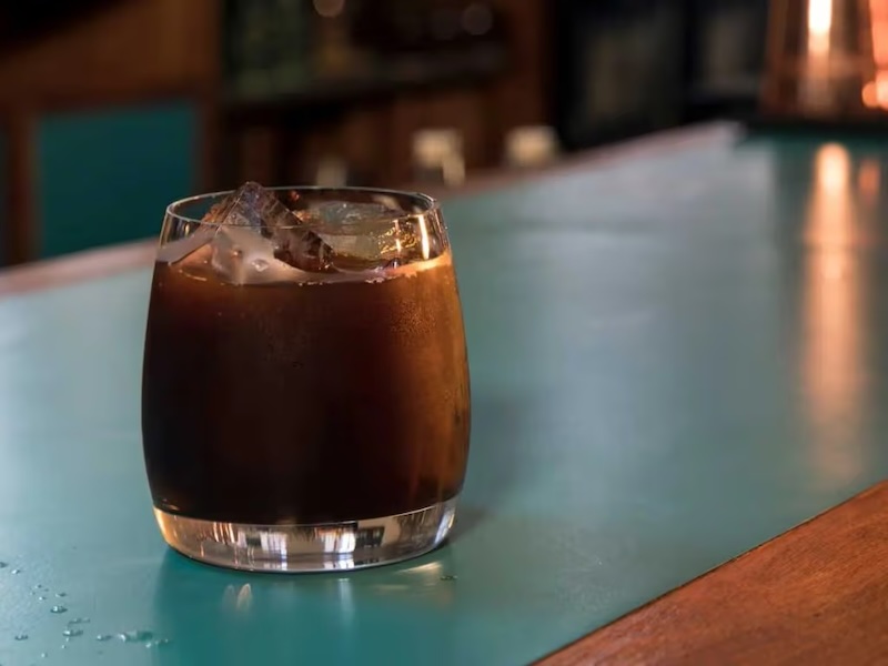 Bow St. Belter cocktail i lavt glas med isterninger og appelsinskal – en farverig og kompleks drink med dybe noter.